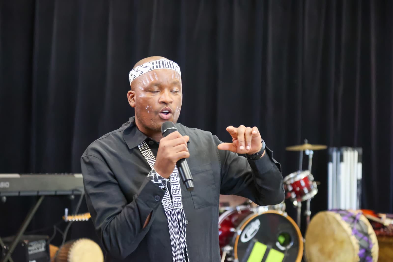 A facilitator in traditional Xhosa dress speaking on stage at a Hub event
