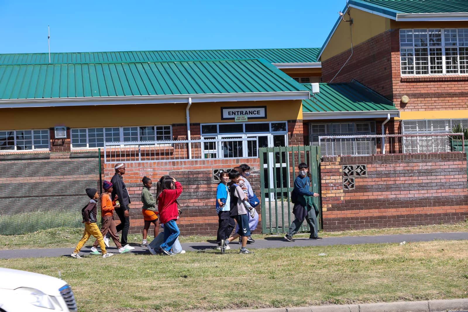 A group walking past a partner school entrance in Langa